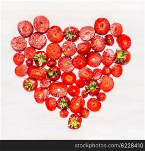 Heart shape sliced Strawberries on white wooden background, top view