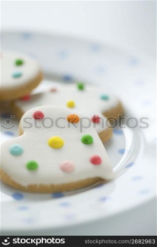 Heart shaped biscuits with icing on top placed on a pola dot plate