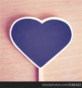 Heart shaped blackboard on wooden background with copy space, retro filter effect