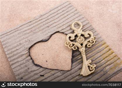 Heart shaped burnt out of a brown cardboard and a key
