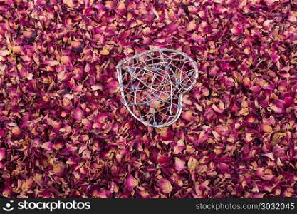 Heart shaped cage on dry rose petals. Heart shaped cage placed on dry rose petals