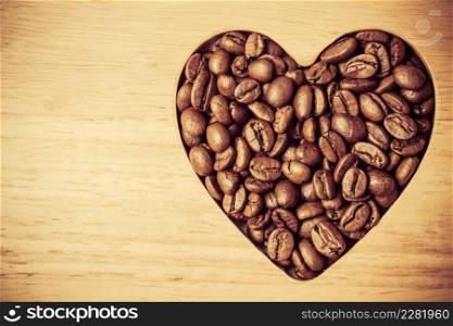 Heart shaped coffee beans on wooden board background. Top view