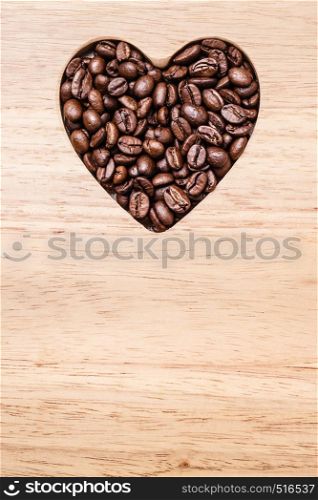 Heart shaped coffee beans on wooden board background. Top view
