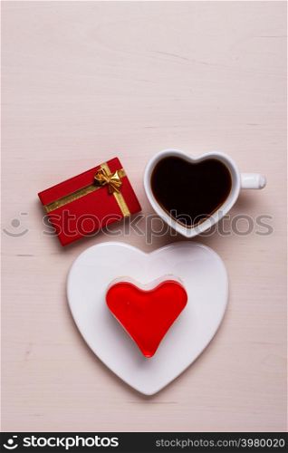 Heart shaped coffee cup jelly cake and red gift box on wooden surface, top view copy space for text