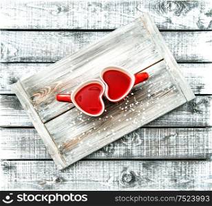 Heart shaped cups with red tea drink on rustic wooden background. Valentines day concept. Vintage style toned picture