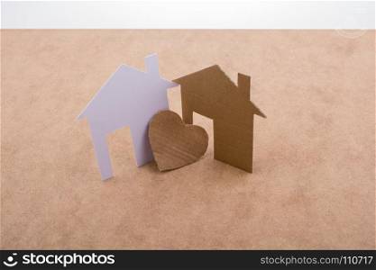 Heart shaped icon and paper houses on a brown background