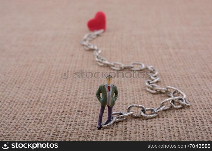 Heart shaped object attached to a man figurine on canvas
