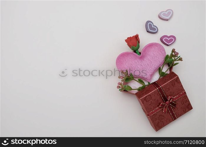 Heart-shaped pillow and mini flower in gift box on pink background, valentine concept.