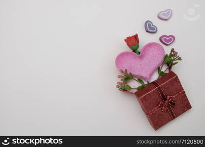 Heart-shaped pillow and mini flower in gift box on pink background, valentine concept.