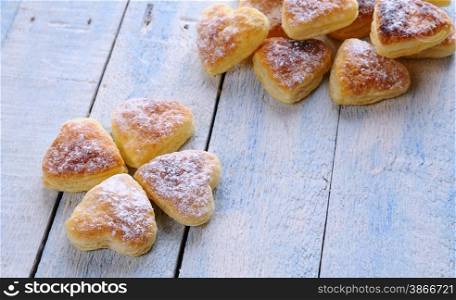 Heart-shaped puff pastry for valentines day over wooden table.