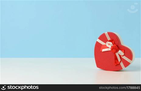 heart shaped red cardboard gift box on white table, festive backdrop, copy space