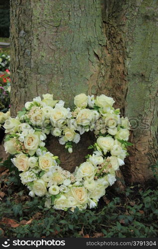 Heart shaped sympathy flowers near a tree