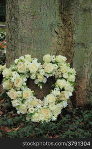 Heart shaped sympathy flowers near a tree