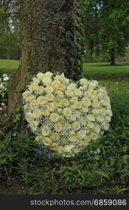 Heart shaped sympathy flowers or funeral flowers near a tree