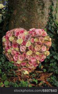 Heart shaped sympathy flowers or funeral flowers near a tree