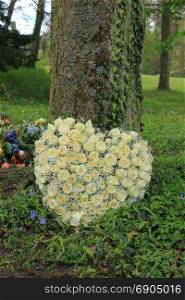 Heart shaped sympathy flowers or funeral flowers near a tree