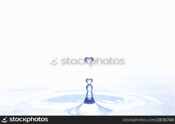 Heart shaped water droplets falling into water