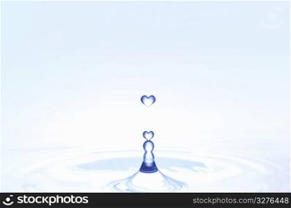 Heart shaped water droplets falling into water