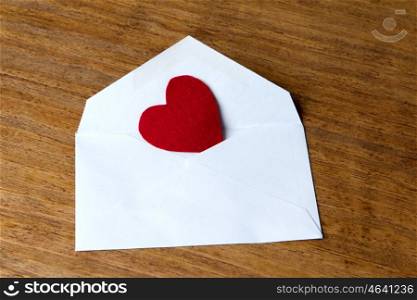 Heart stuffed in an envelope on a wooden background