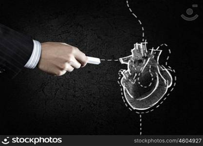 Heart surgery. Hand drawing human heart with chalk on black