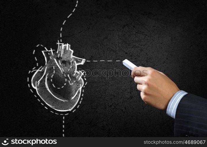 Heart surgery. Hand drawing human heart with chalk on black