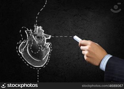 Heart surgery. Hand drawing human heart with chalk on black