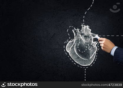 Heart surgery. Hand drawing human heart with chalk on black