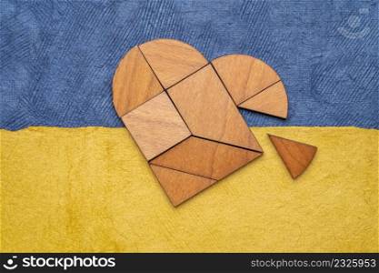 heart tangram against paper abstract in colors of Ukrainian national flag - blue and yellow, support Ukraine concept