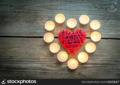 Heart with burning candles on the wooden background
