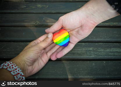 Heart with rainbow stripes in male hands. LGBT pride flag, symbol of lesbian, gay, bisexual, transgender for social movements. Homosexual love,Equality or Human rights concept. Copy space.. Decorative Heart with rainbow stripes in male hands. LGBT pride flag, symbol of lesbian, gay, bisexual, transgender for social movements. Homosexual love, Human rights concept. Copy space.