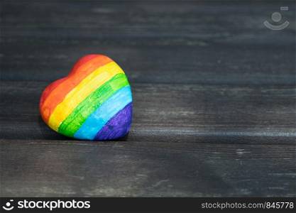 Heart with rainbow stripes on dark wooden background. LGBT pride flag, symbol of lesbian, gay, bisexual, transgender for social movements. Homosexual love,Equality or Human rights concept. Copy space.. Decorative Heart with rainbow stripes on dark wooden background. LGBT pride flag, symbol of lesbian, gay, bisexual, transgender for social movements. Homosexual love, Human rights concept. Copy space.