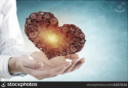 Heart working like engine. Male hands holding heart made of gears and cogs