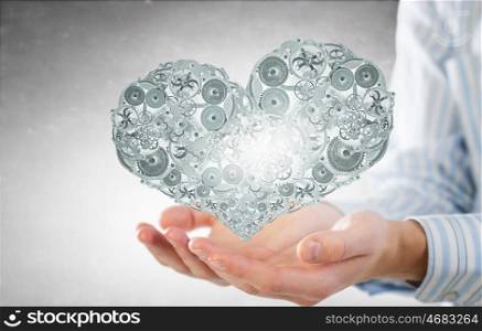 Heart working like engine. Male hands holding heart made of gears and cogs