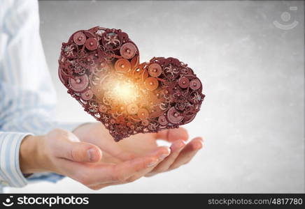 Heart working like engine. Male hands holding heart made of gears and cogs