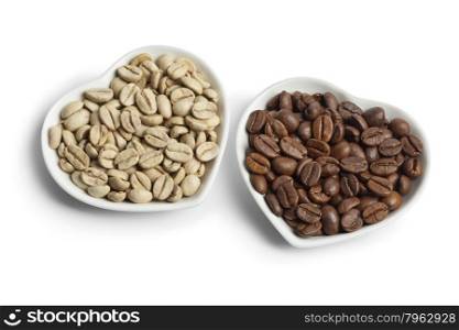 Heartshaped bowls with Indian Malabar green unroasted and brown roasted coffee beans on white background