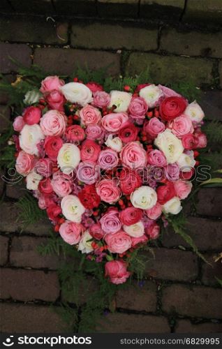 Heartshaped sympathy flowers or funeral flowers near a tree