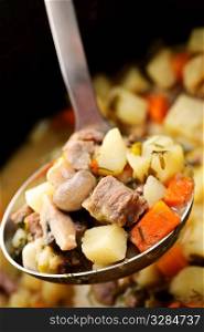 Hearty beef and potatoes stew with vegetables served with ladle