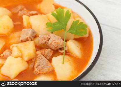 Hearty beef stew simmering on gray wooden background