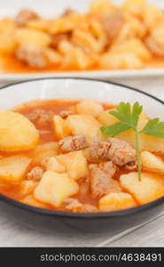 Hearty beef stew simmering on gray wooden background