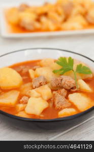 Hearty beef stew simmering on gray wooden background