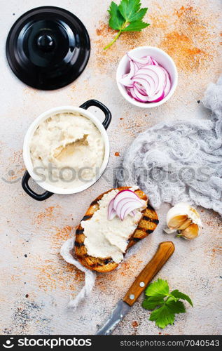 Hearty lard with garlic served with fresh bread on a rustic white table.