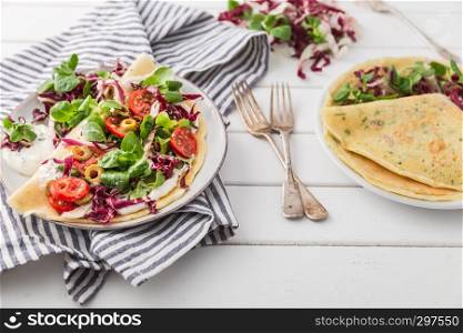 hearty pancakes with fresh salad, tomato and radicchio, top view