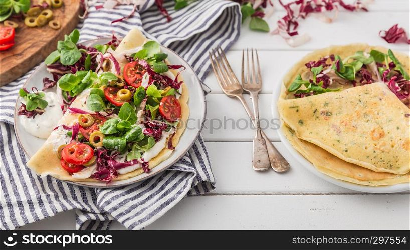 hearty pancakes with fresh salad, tomato and radicchio, top view