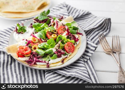 hearty pancakes with fresh salad, tomato and radicchio, top view