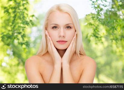 heath and beauty concept - beautiful woman touching her face skin over green natural background. beautiful woman touching her face skin