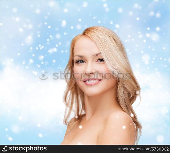 heath, people and beauty concept - beautiful young woman with bare shoulders over blue sky, snow and clouds background