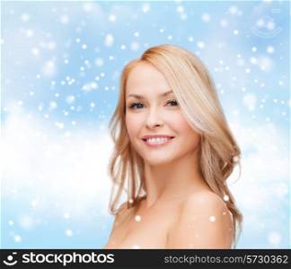 heath, people and beauty concept - beautiful young woman with bare shoulders over blue sky, snow and clouds background