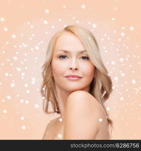 heath, people and beauty concept - beautiful young woman with bare shoulders over beige snowy background