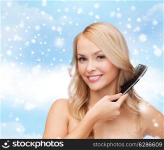 heath, people, haircare and beauty concept - beautiful young woman with bare shoulders combing her hair over blue sky, snow and clouds background