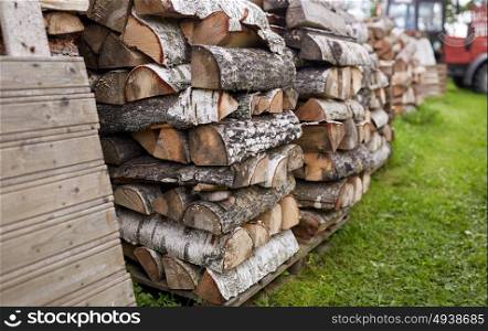 heating, agriculture and farming concept - stack of firewood on farm at country. stack of firewood on farm at country